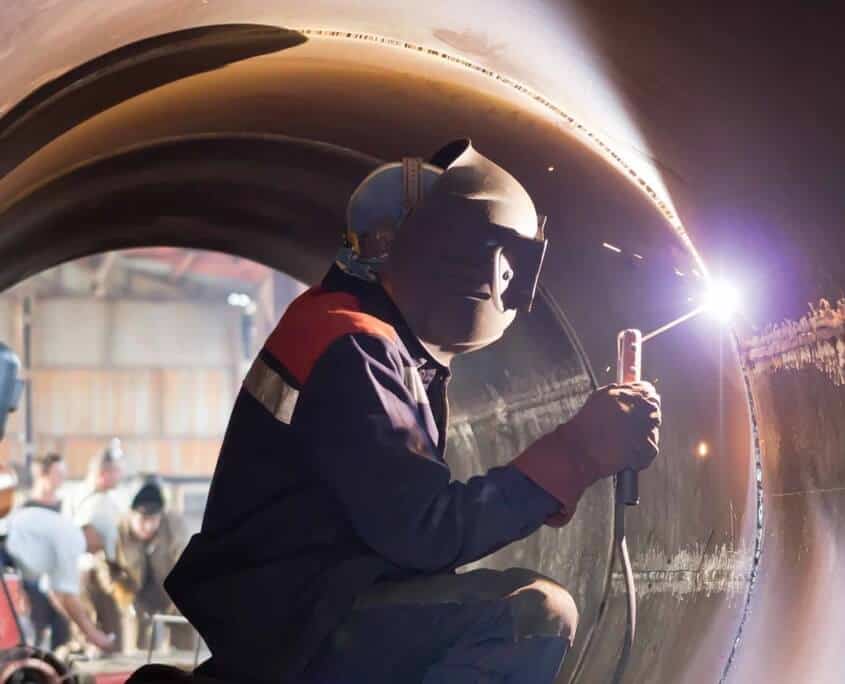 metal welder working on a large metal tube